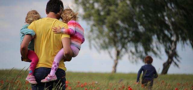 man carrying to girls on field of red petaled flower by Juliane Liebermann courtesy of Unsplash.