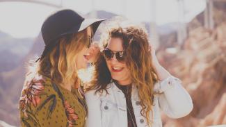 two women smiling while wearing sunglasses by Katie Treadway courtesy of Unsplash.