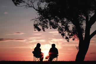 silhouette of two person sitting on chair near tree by Harli  Marten courtesy of Unsplash.